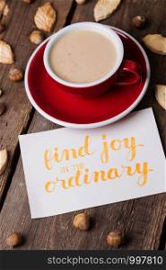 red cup of coffee and leaf shape cookies with the inscription find joy in the ordinary