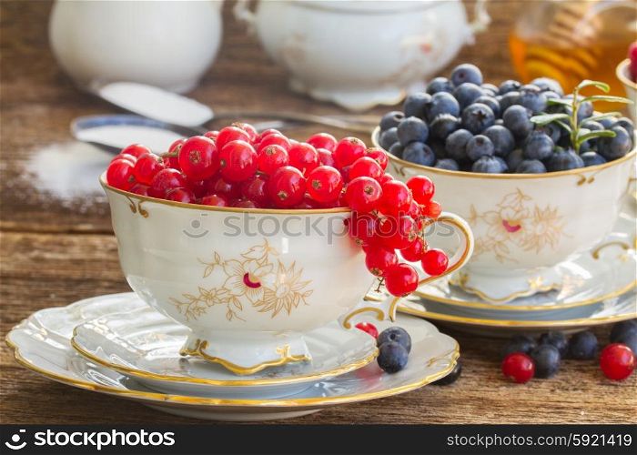 red currant and blueberry in cups . red currant and blueberry in cups on wooden table