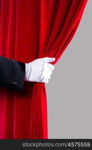 Red curtain. Close up of hand in white glove open the curtain. Place for text