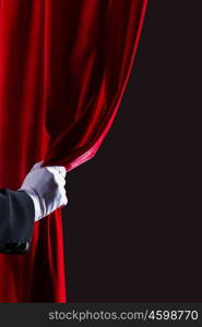 Red curtain. Close up of hand in white glove open the curtain. Place for text