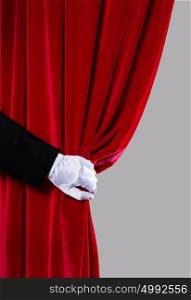 Red curtain. Close up of hand in white glove open the curtain. Place for text