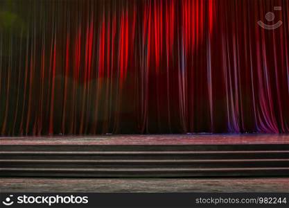 Red curtains and the stage parquet with stairs in theater with colorful lighting.