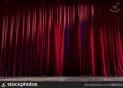 Red curtains and the wooden stage in a theater.
