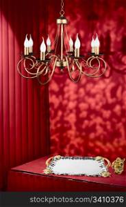Red dark corner with vignette and retro walls. Vintage lamp, tray and golden asian fat man with smile. Smiling statye is a symbol of wealth