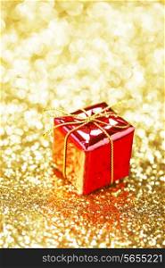 Red decorative box with holiday gift on abstract gold background