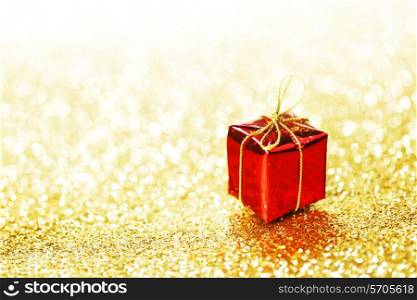Red decorative box with holiday gift on gold glitters background
