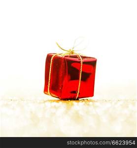 Red decorative box with holiday gift on gold glitters background