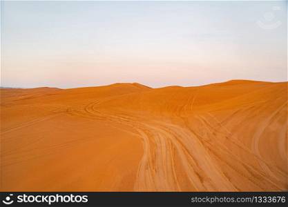 Red Desert Safari with sand dune in Dubai City, United Arab Emirates or UAE. Natural landscape background at sunset time. Famous tourist attraction. Pattern texture of sand with blue sky.