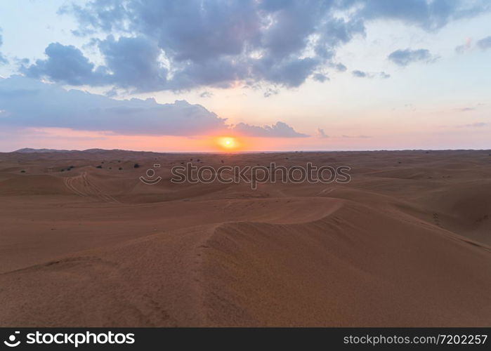 Red Desert Safari with sand dune in Dubai City, United Arab Emirates or UAE. Natural landscape background at sunset time. Famous tourist attraction. Pattern texture of sand with blue sky.