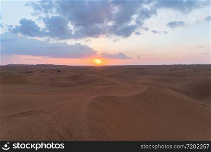Red Desert Safari with sand dune in Dubai City, United Arab Emirates or UAE. Natural landscape background at sunset time. Famous tourist attraction. Pattern texture of sand with blue sky.