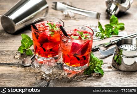 Red drink with strawberry, mint leaves, ice. Cocktail making bar accessories
