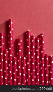 Red drinking straws on white points. Background of straws and bright colour paper. Arranged straws next to each other. Concept for Summer time and drinking. Geometric backdrop.