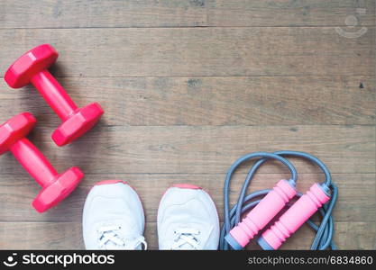 Red dumbbells, jump rope and sport shoes on wood background with copy space, Healthy lifestyle concept