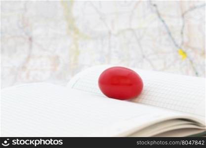Red egg on ledger pages with map behind shows troubled financial and business times. Selective focus on key, nest egg symbol.