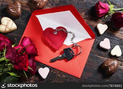 Red envelop, roses, chocolate and key On old wood background