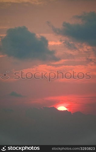 Red evening sunset over the ocean hidden behind the clouds