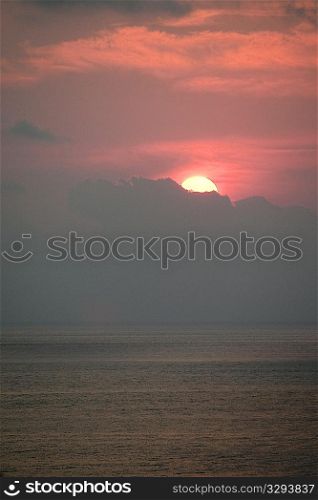 Red evening sunset over the ocean hidden behind the clouds