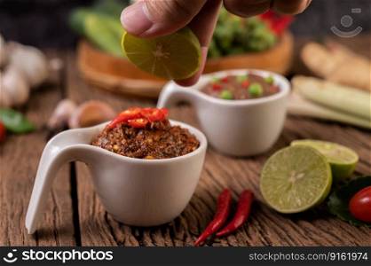 Red Eye Chili Paste with Lemon and Chili on Wooden Floor.
