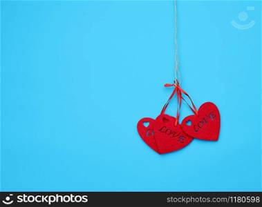 red felt hearts hanging on a brown rope, blue background. Holiday celebration concept.
