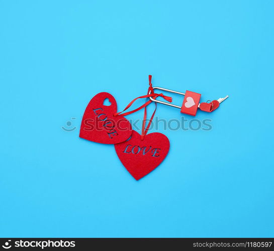 red felt hearts hanging on an iron lock, blue background. Holiday celebration concept.