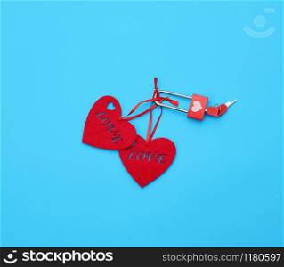 red felt hearts hanging on an iron lock, blue background. Holiday celebration concept.