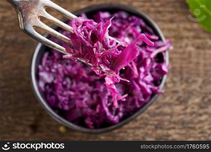 Red fermented cabbage on a fork, close up