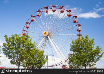 Red Ferris Wheel against blue sky at amusement park