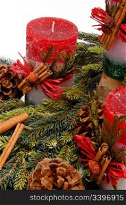 Red festive candles with green cedar leaves & cinnamon tied on with twine among fresh green pine branches. . Mark Skalny Photgraphy