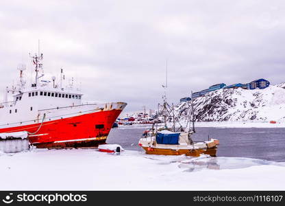 Red fishing boat anchored in the snow lagoon. port of Nuuk, Greenland