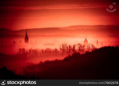 Red foggy dawn in town of Krizevci, church towers in fog, Prigorje region of Croatia