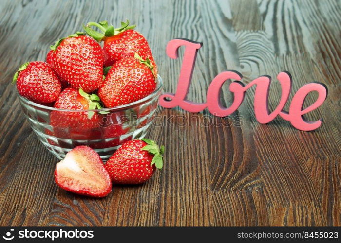 Red fresh strawberry in a bowl on brown wooden background. Strawberry in a bowl on brown wooden background