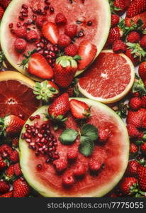 Red fruits and berries background with watermelon, grapefruit, strawberries, raspberries and pomegranate seeds. Healthy summer food. Top view.