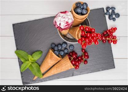 Red fruits ice cream cone on wooden table.