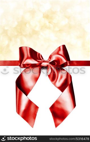 Red gift bow on white. Red gift ribbon bow and golden bokeh isolated on white background