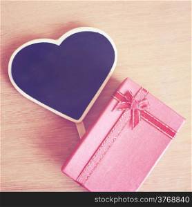 Red gift box and heart shaped blackboard with copy space, retro filter effect