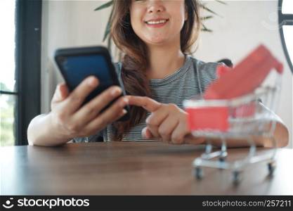 red gift box on shopping cart with women using mobile phone