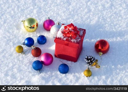 Red gift box on snow with christmas balls