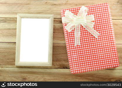 Red gift box with empty wooden picture frame on wood background.. Red gift box with empty wooden picture frame on wood background,concept of christmas and Important day.