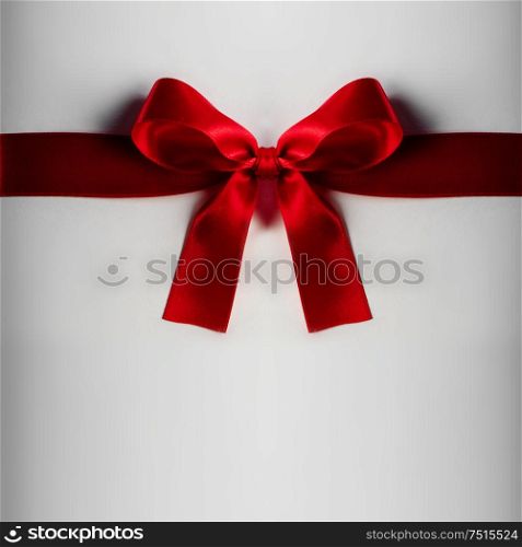 Red gift satin bow on light background. Red gift bow on white