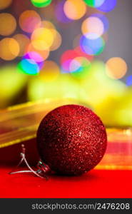 Red glittery decoration in a colorful Christmas composition isolated on background of blurred lights.