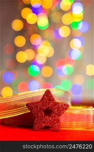 Red glittery decoration in a colorful Christmas composition isolated on background of blurred lights.