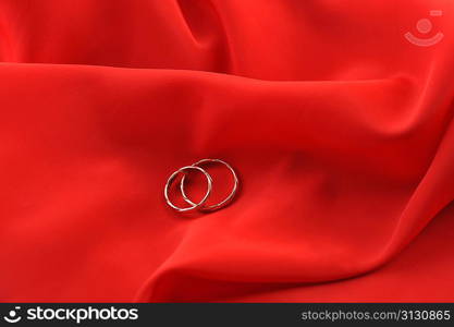 red graceful fabric and gold wedding rings close up