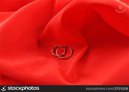 red graceful fabric and gold wedding rings close up