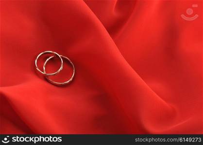 red graceful fabric and gold wedding rings close up