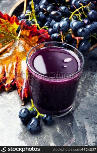 Red grape juice in glass and grape fruit. Grape drink in a glass
