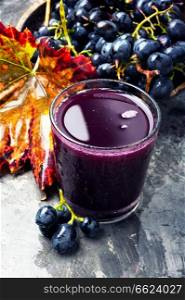 Red grape juice in glass and grape fruit. Grape drink in a glass