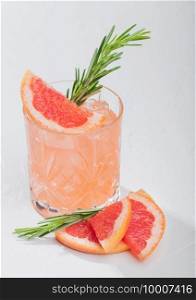 Red grapefruit cocktail with fruit slice and rosemary on white background. Space for text