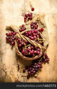 Red grapes in a basket. On a wooden table.. Red grapes in a basket.