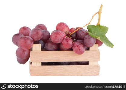 Red grapes in wooden crate isolated on white background.
