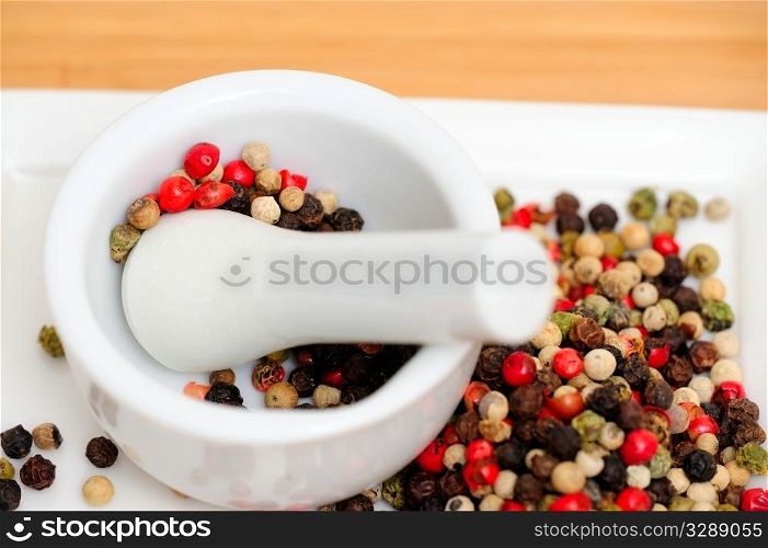 Red Green And Black Peppercorns. Peppercorns in various colors of red, green and the familiar black peppercorn on white with a Mortar and Pestle
